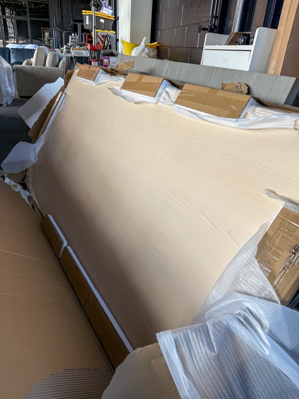 Wood table top in opened factory packaging with foam wrap on the warehouse floor